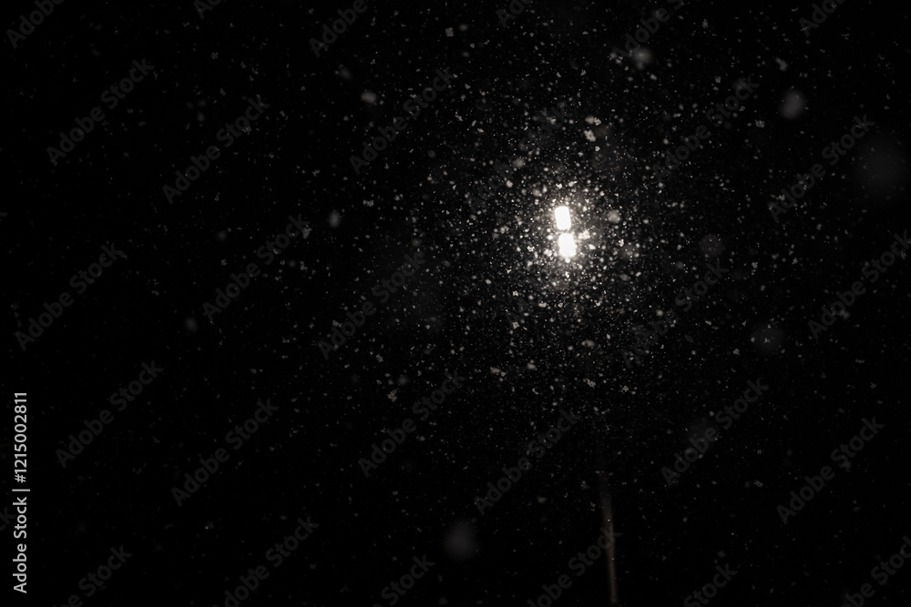 Fototapeta premium Lantern lighting against the backdrop of heavy snowfall at night. Night view of a lantern and snow.