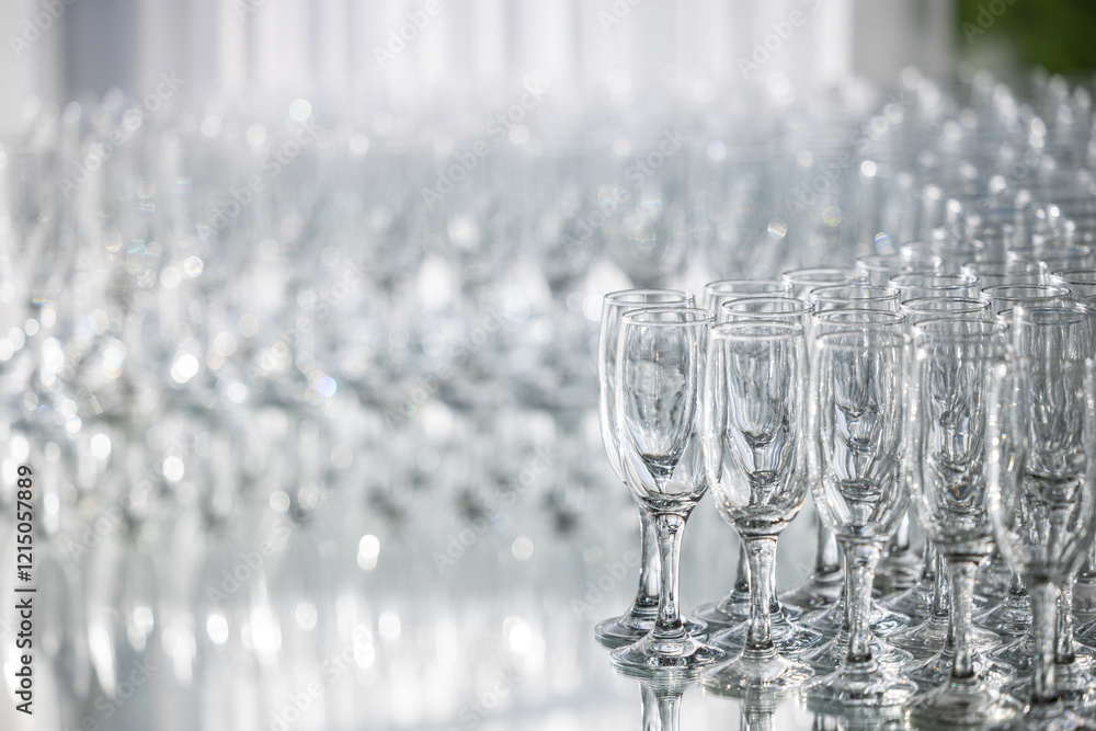 Rows of crystal glasses neatly arranged on a reflective surface, ideal for events, catering, or luxury dining. A lot of glasses for champagne and welcoming guests.
