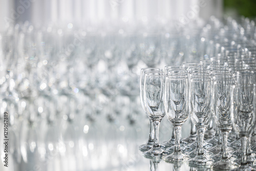 Obraz na płótnie Rows of crystal glasses neatly arranged on a reflective surface, ideal for events, catering, or luxury dining. A lot of glasses for champagne and welcoming guests. w salonie