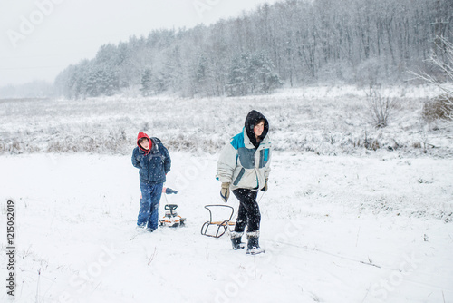 Children enjoying a snowy day while pulling a sled through a winter landscape