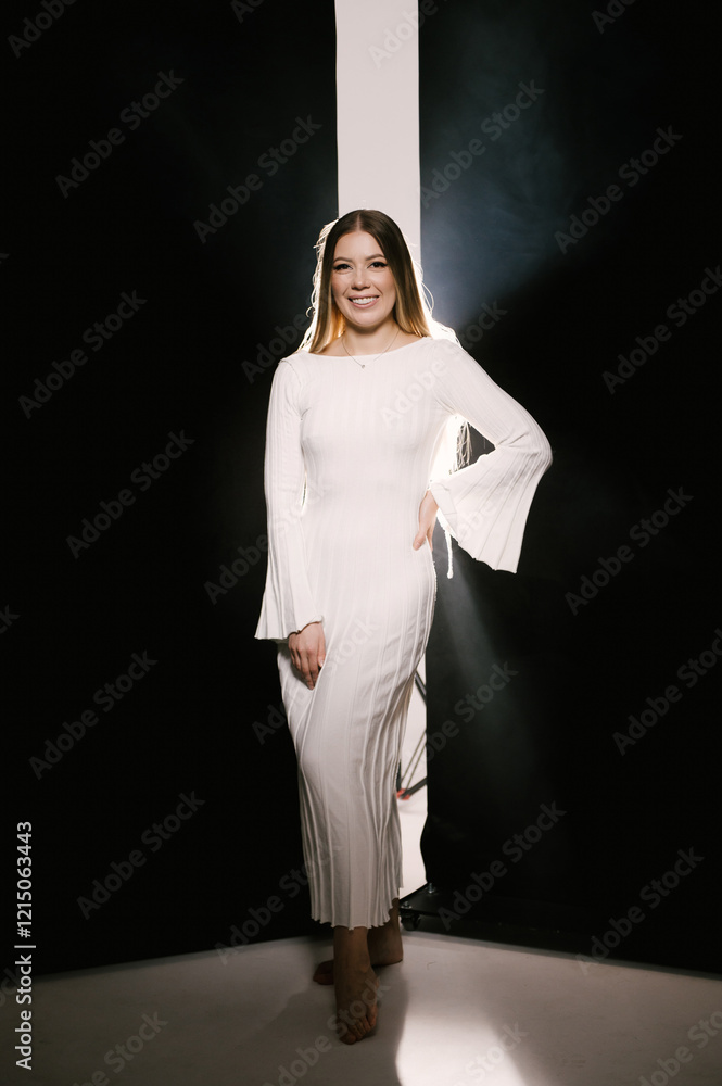 Portrait of a woman in a studio with professional lighting in a white long dress, soft focus