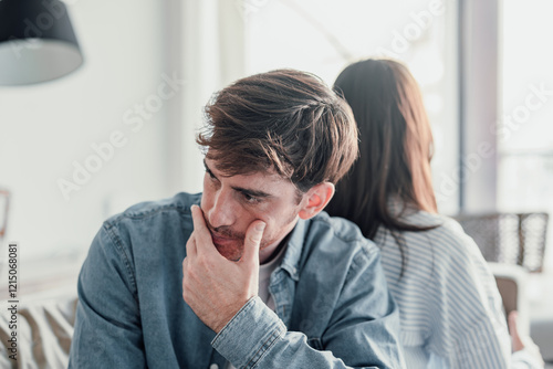 Beautiful lady is depressed, sitting on the couch talking to man, having a dispute with husband or girlfriend, looking desperate and hopeless, having unresolved problem or question. photo