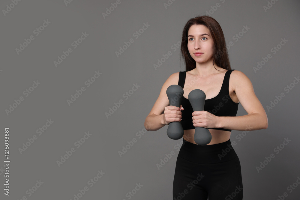 Woman in sportswear exercising with dumbbells on grey background, space for text Woman in sportswear exercising with dumbbells on grey background, space for text