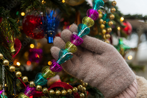 Canvas-taulu Colorful holiday decorations adorn a Christmas tree as a hand adds a festive tou