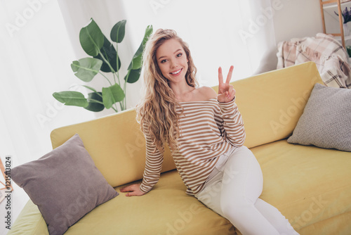 Fényképezés Young woman with blond hair relaxing at home, wearing a striped pullover, enjoyi
