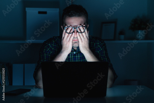 Man with eye strain computer problem at night