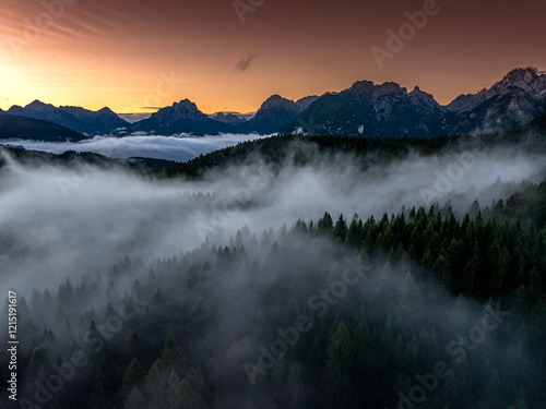 Obraz na płótnie Sunrise aerial photo over the Dolomites with vibrant hues on the Antelao and Cridola peaks, framed by dense alpine forests below. Captured near Danta village, Italy. Hiking in Italy. w salonie