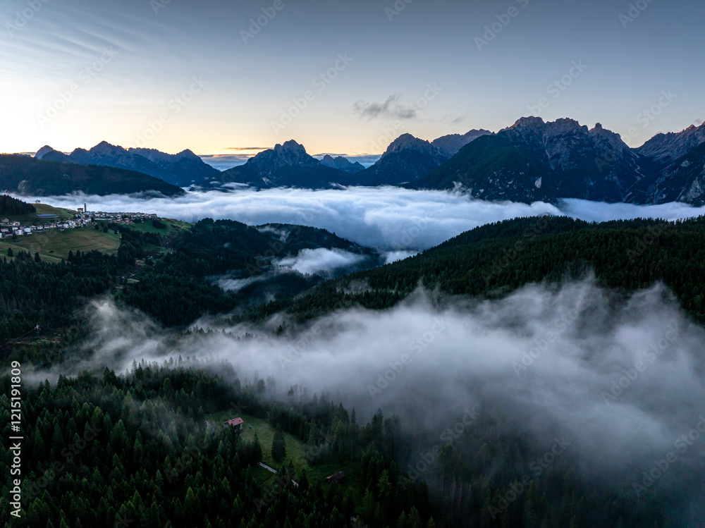 Scenic aerial morning view of misty valleys and forested landscapes in the Dolomites, with Antelao and Cridola peaks in the background. Captured near Danta village, Italy. Hiking in Dolomites.