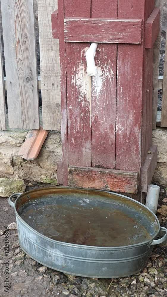 A beautifully rustic wooden water well featuring a charming metal basin for collecting water