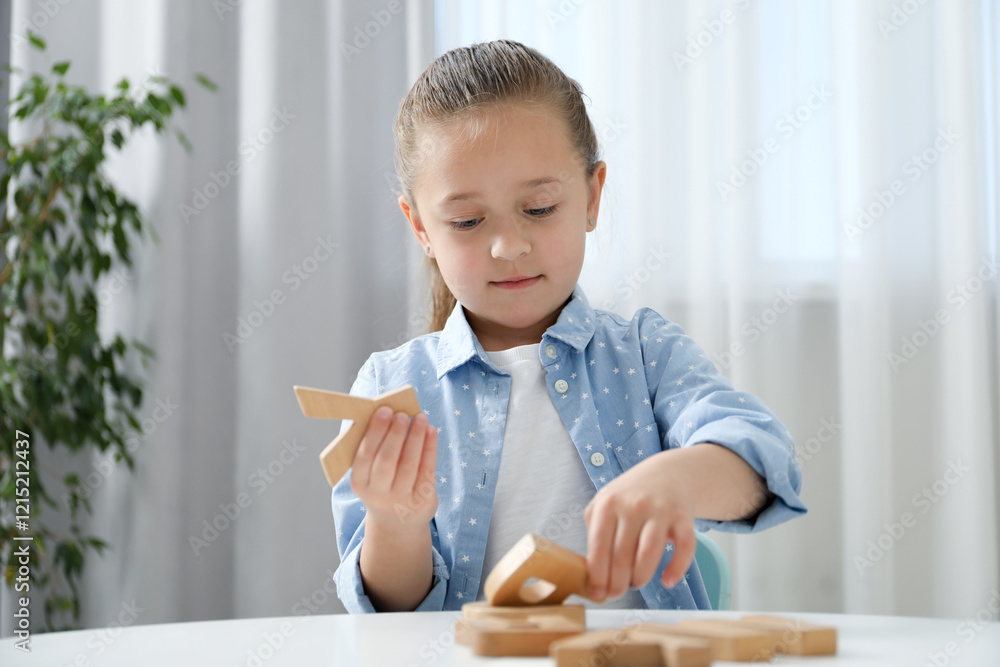Little girl learning alphabet with wooden letters at white table indoors Little girl learning alphabet with wooden letters at white table indoors