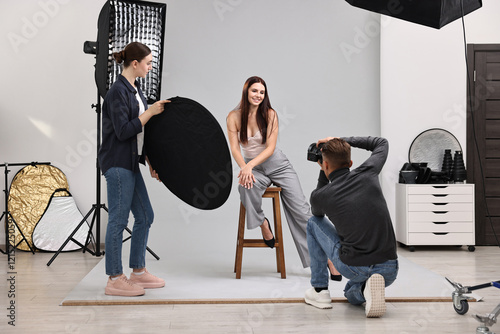 Photographer and assistant working with model in professional photo studio