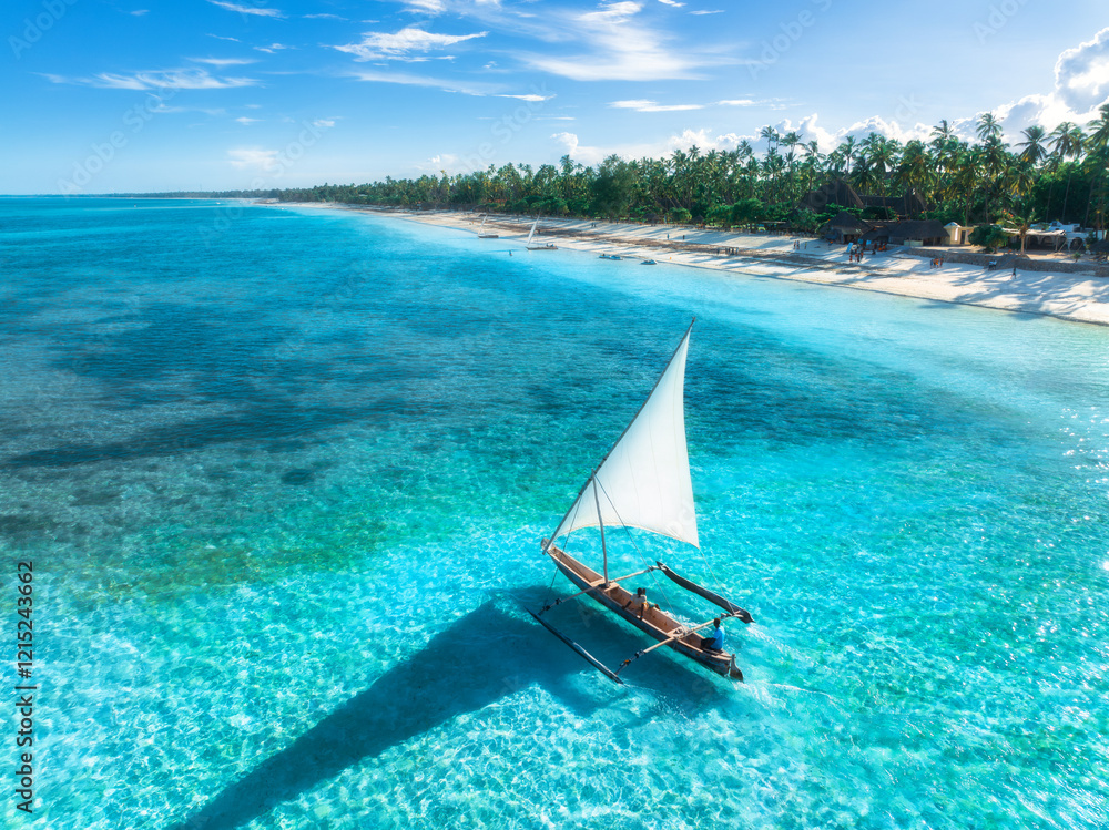 Obraz premium Aerial view of the sailboat on blue sea, empty white sandy beach at sunrise. Summer vacation in Zanzibar. Tropical landscape with boat, ocean with clear water, green palms, sky. Top drone view. Exotic