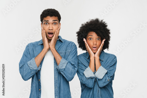 Young shocked scared couple two friends family man woman of African American ethnicity wear denim casual clothes together look camera cover cheek with hands isolated on white color background