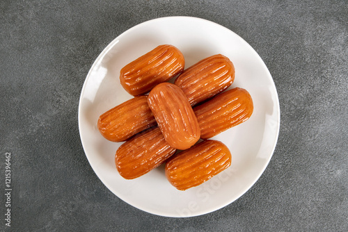 Traditional Turkish dessert tulumba on a plate. Tulumba dessert, fried in oil and soaked in syrup photo