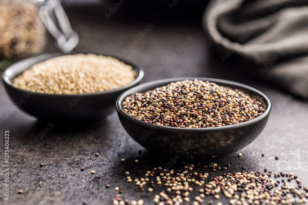Mixed uncooked quinoa seeds in bowl on black table. Mixed uncooked quinoa seeds in bowl on black table.
