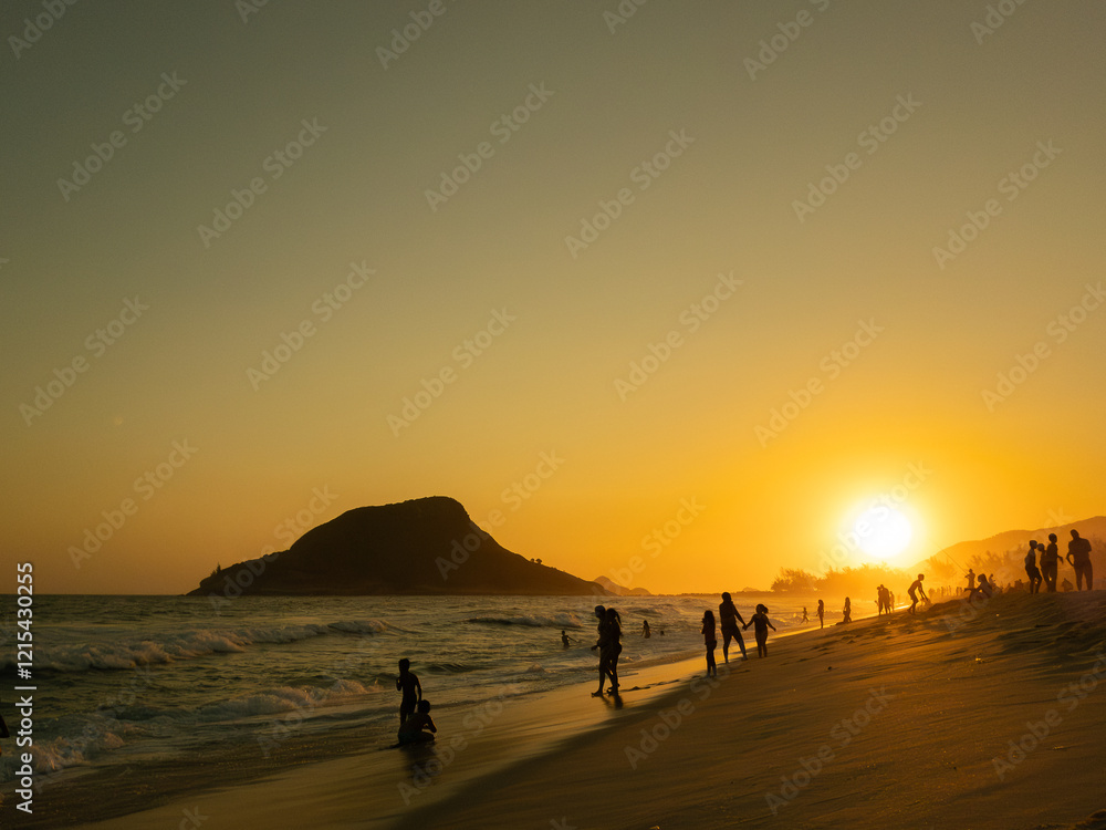 Pessoas aproveitando na baira do mar com pôr do sol na praia com montanha ao fundo Pessoas aproveitando na baira do mar com pôr do sol na praia com montanha ao fundo