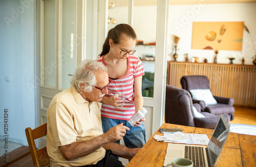 Grandfather helping granddaughter with laptop work in kitchen photo