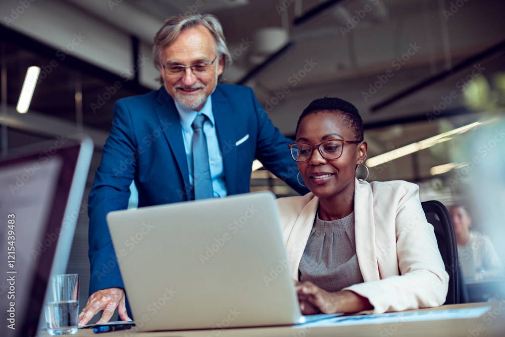 Diverse coworkers collaborating on laptop in modern office setting Diverse coworkers collaborating on laptop in modern office setting