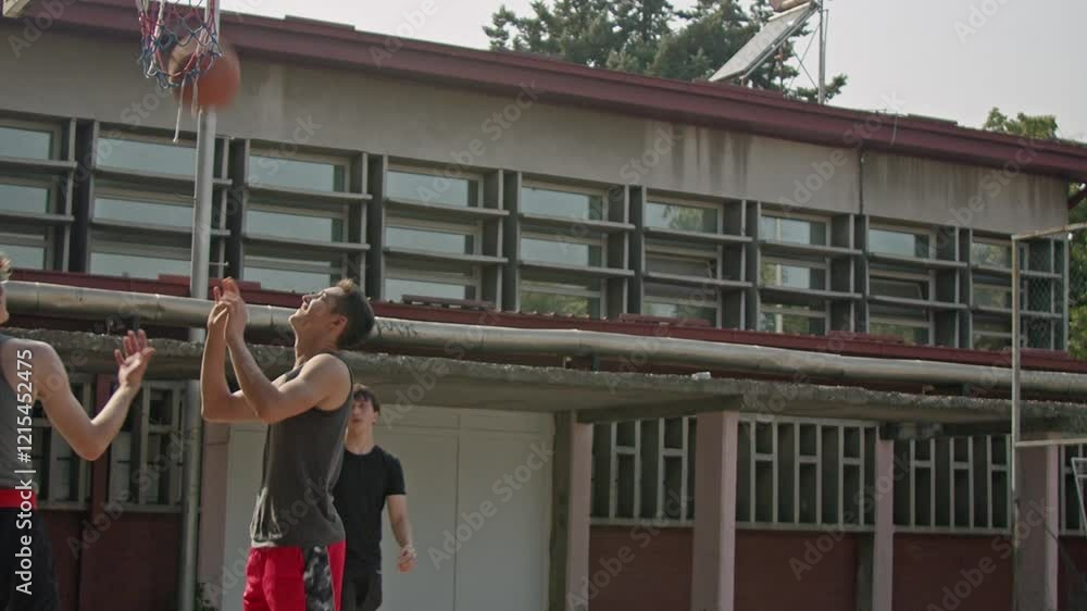 Teenage friends playing basketball in the schoolyard. Slow-motion shot of friends playing basketball. Teenage friends playing basketball in the schoolyard. Slow-motion shot of friends playing basketball.