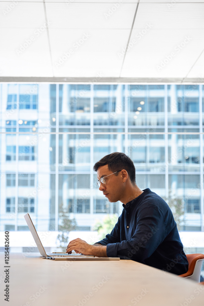 Busy young professional business man executive, male corporate employee, Hispanic businessman investor or manager typing on computer technology using laptop working at office desk at window. Vertical Busy young professional business man executive, male corporate employee, Hispanic businessman investor or manager typing on computer technology using laptop working at office desk at window. Vertical