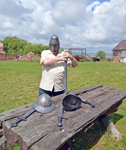 KALININGRAD REGION, RUSSIA. A tourist with a helmet on his head holds a knight's sword. Brandenburg Castle, 13th century. photo