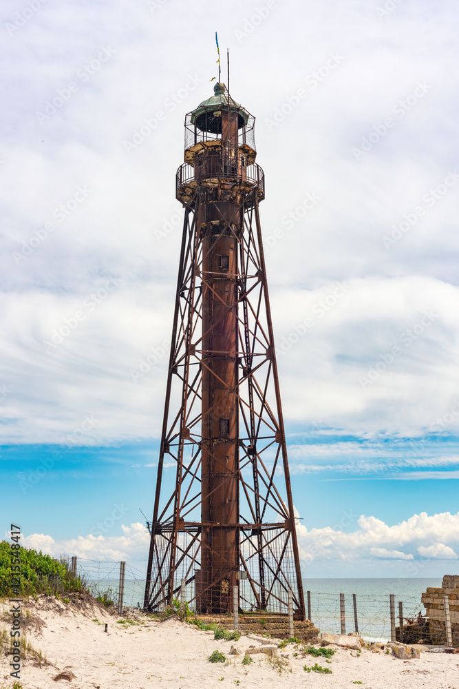 An old rusty abandoned lighthouse and a ruined building on the Dzharylhach island on the Black Sea coast