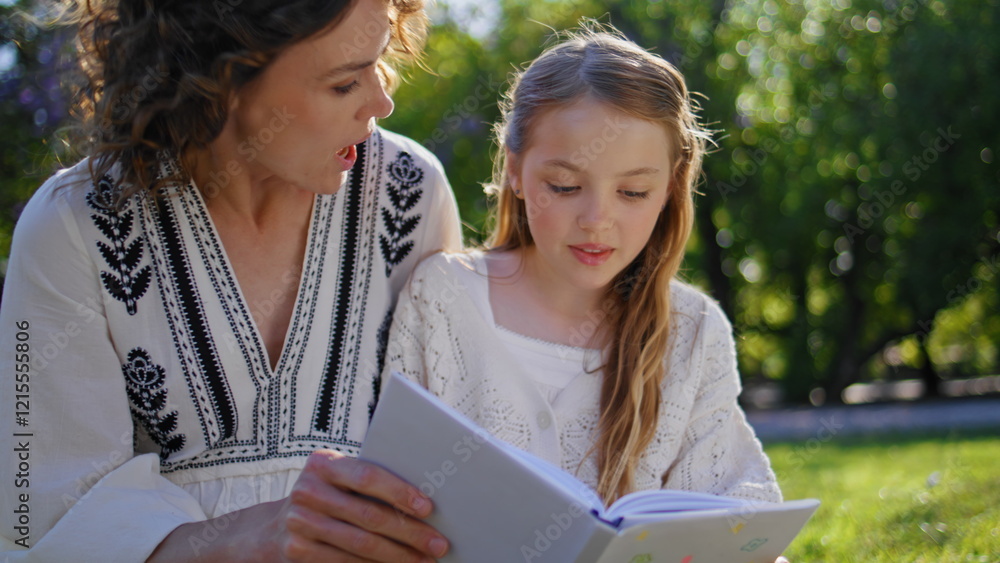 Happy family reading book gathering in cozy garden closeup. Woman girl resting Happy family reading book gathering in cozy garden closeup. Woman girl resting