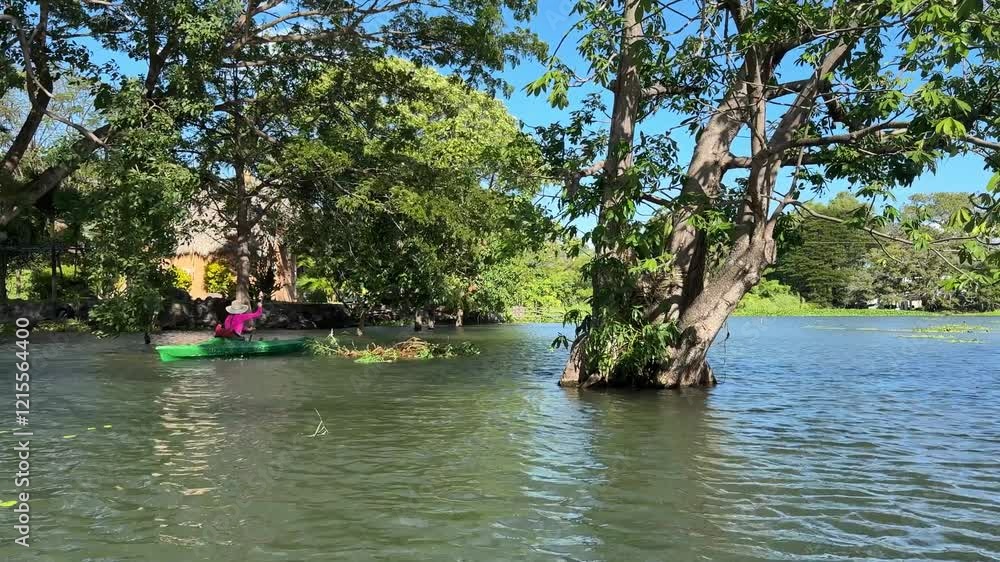 A smiling woman experiences the joy of kayaking on Lake Nicaragua, surrounded by lush greenery and enjoying the warm weather in Granada, Central America. A smiling woman experiences the joy of kayaking on Lake Nicaragua, surrounded by lush greenery and enjoying the warm weather in Granada, Central America.