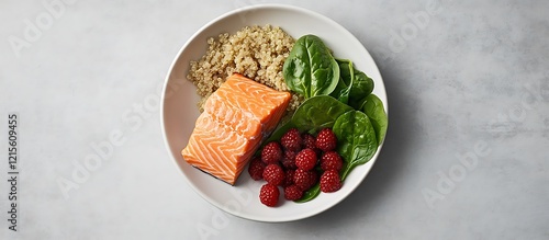 A well-balanced heart-healthy meal with quinoa, salmon, spinach, and a handful of berries, captured from above on a soft grey background for a minimalist, clean aesthetic. photo