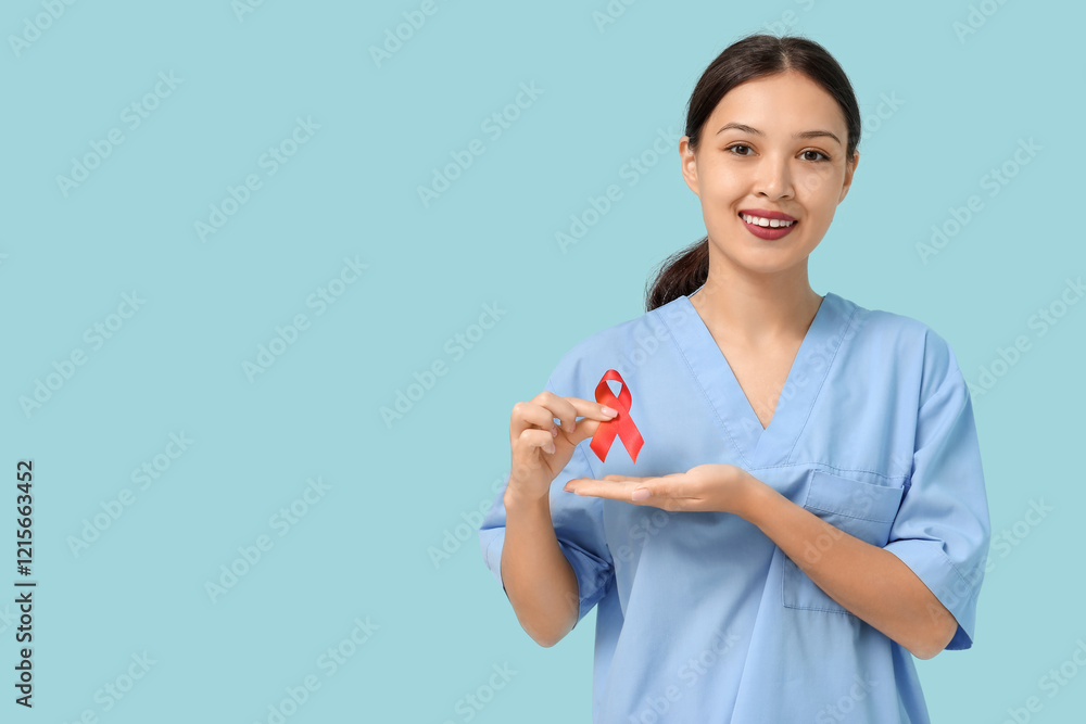 Young female doctor with red ribbon on blue background. World AIDS day concept Young female doctor with red ribbon on blue background. World AIDS day concept