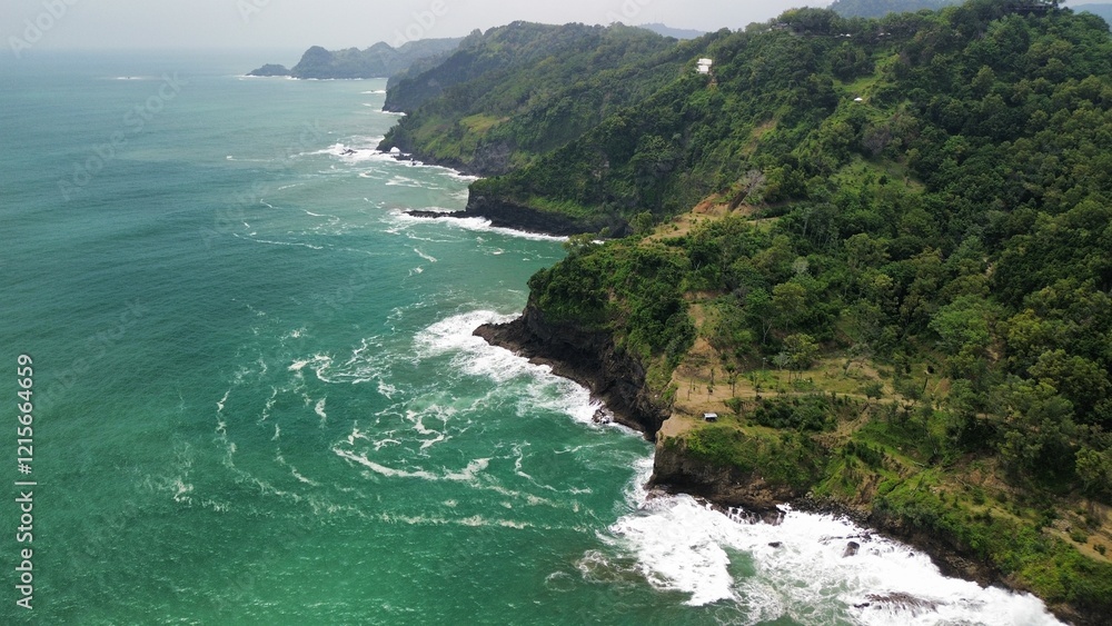 Aerial drone view of coastline with hills and trees, as well as view of coral cliffs and sea with waves from the ocean in Sagara view also known as Karang Bolong Beach Kebumen Central Java Indonesia Aerial drone view of coastline with hills and trees, as well as view of coral cliffs and sea with waves from the ocean in Sagara view also known as Karang Bolong Beach Kebumen Central Java Indonesia