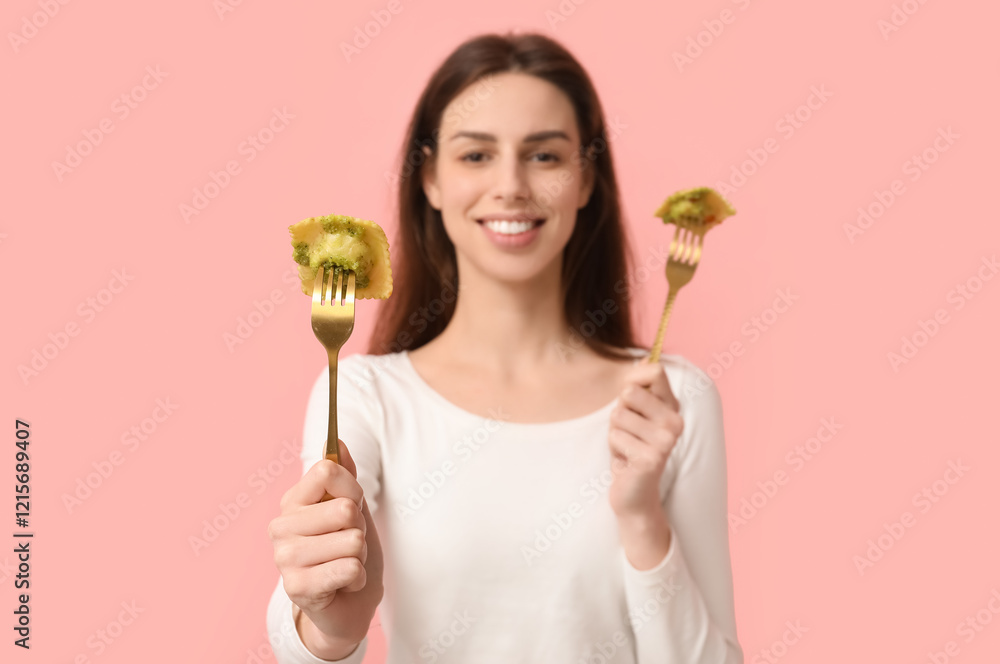 Beautiful young woman holding forks with tasty ravioli on pink background