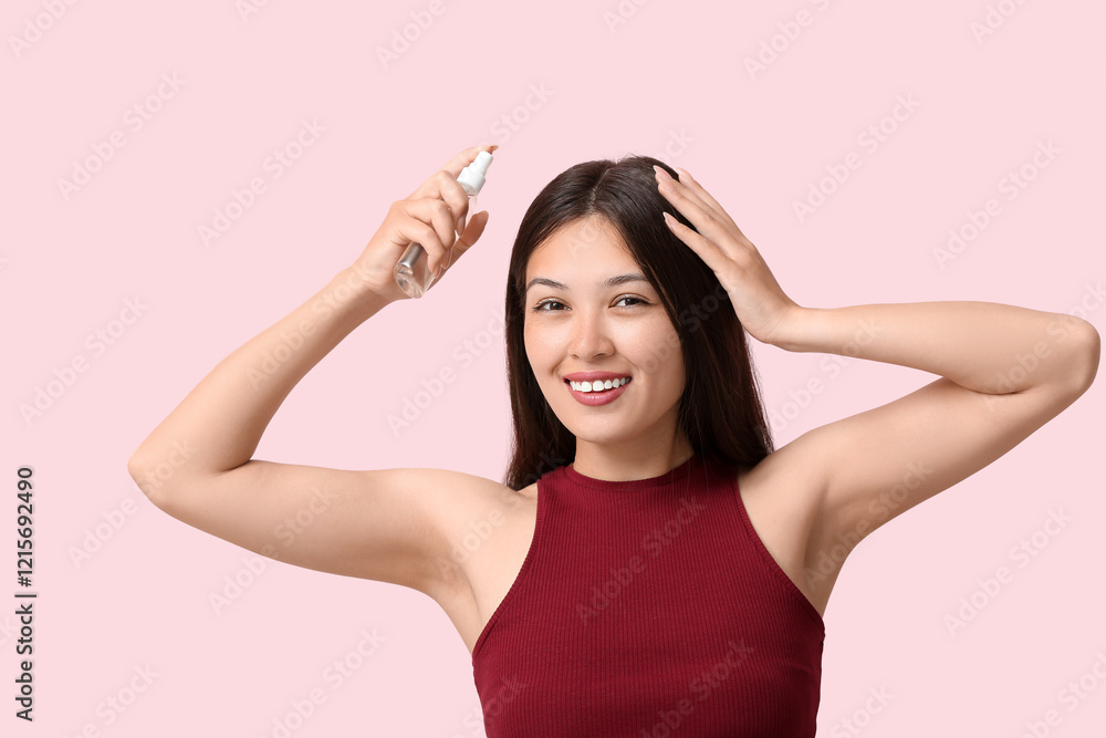 Beautiful young happy woman applying hair spray on pink background Beautiful young happy woman applying hair spray on pink background