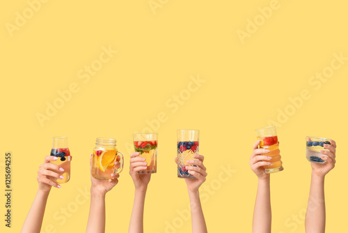 Many hands with infused water on yellow background photo