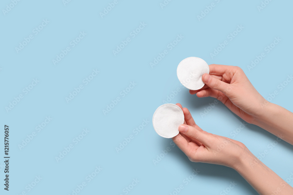 Young woman holding cotton pads on blue background Young woman holding cotton pads on blue background