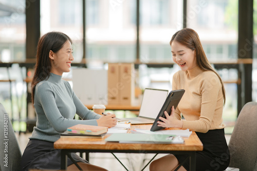 Two Asian business women discuss and discuss company paperwork. in the office room