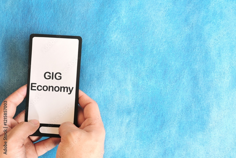 Human hand holding mobile phone with written phrase gig economy. Gig economy concept.