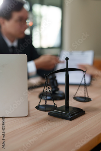 A focused, close-up shot of a black metal justice scale standing on a wooden desk, symbolizing law and equity.