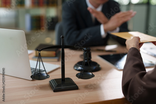A focused, close-up shot of a black metal justice scale standing on a wooden desk, symbolizing law and equity.