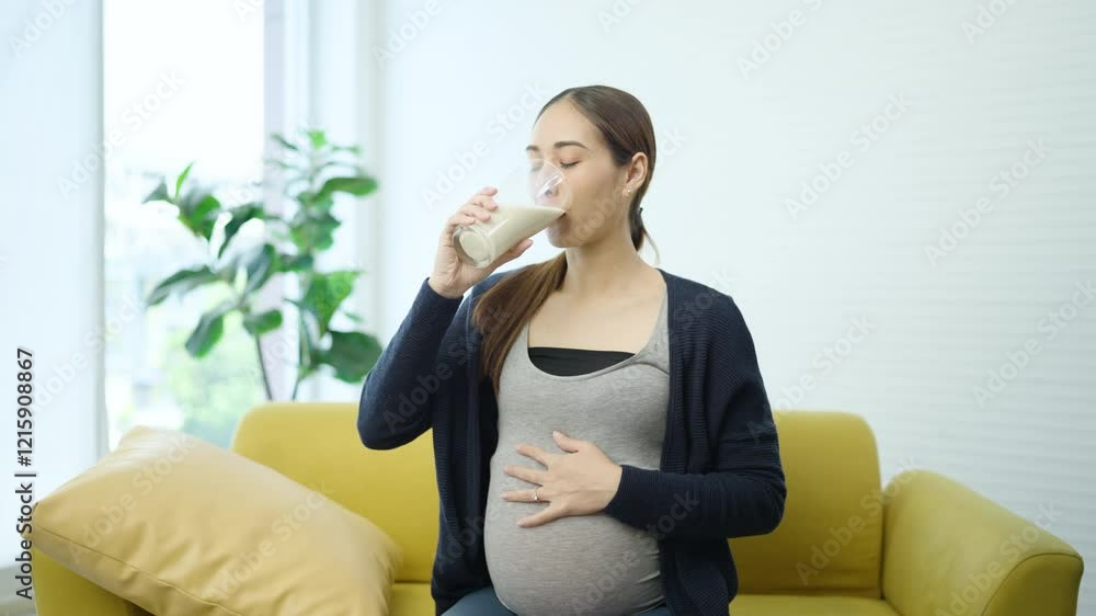 Pregnant Woman Drinking Milk for Healthcare to Baby. Asian Pregnant Sitting on Yellow Couch. Healthy Nutrition, Prenatal Care, Family, Relaxed, Expecting Mother and Wellness. Pregnant Woman Drinking Milk for Healthcare to Baby. Asian Pregnant Sitting on Yellow Couch. Healthy Nutrition, Prenatal Care, Family, Relaxed, Expecting Mother and Wellness.