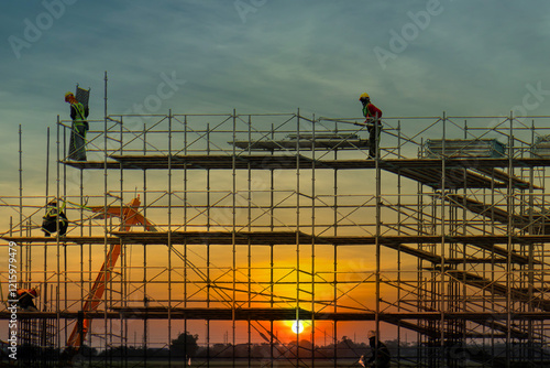Man working on construction site with scaffold and building with sun set background,scaffolding for construction factory