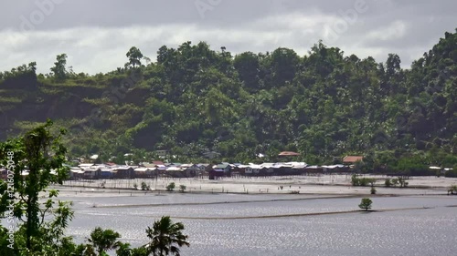 A wide landscape shot captures shrimp farmers tending to their ponds near Settlers Village in Surigao City, Philippines. The pasayan shrimp farming thrives in a coastal, tropical setting. photo