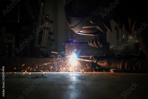 Obraz na płótnie a person wearing a welding mask works on metal with a welding torch, creating sparks through the welding process w salonie