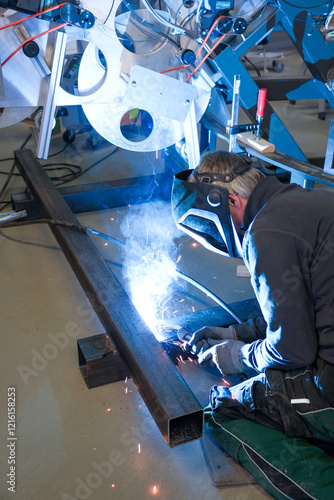 Obraz na płótnie a person wearing a welding mask works on metal with a welding torch, creating sparks through the welding process w salonie
