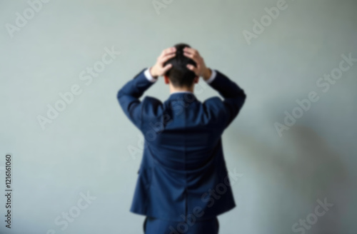 blur background of Rear view of business man standing in front of a wall hands on head wondering what to do next. Full length of businessman facing the wall  photo