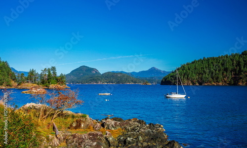 Vancouver Canada, Bowen Island. Boat and yacht in the bay of  northern sea against the background of mountain range, blue sky and wooded islands  