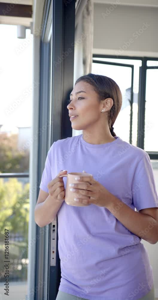 Vertical video: Relaxing at home, woman holding coffee mug and looking out window