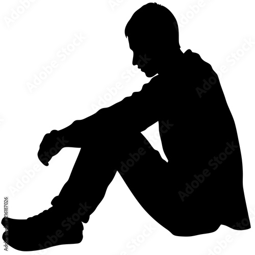 A man is sitting on the ground. He is wearing a black shirt and black pants. He is looking down
