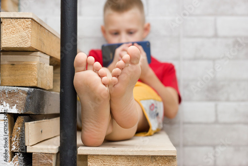 Картината върху платно The boy's feet are close, playing on the phone