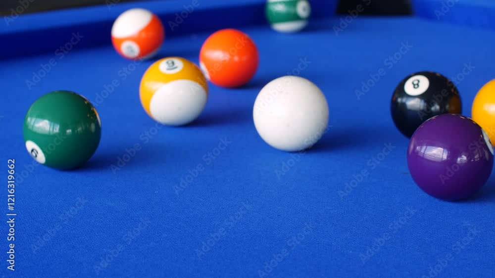 Vibrant close-up of a pool game in action, featuring a cue ball striking colorful billiard balls on a blue felt table Vibrant close-up of a pool game in action, featuring a cue ball striking colorful billiard balls on a blue felt table